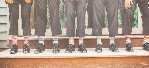 five-men-wearing-colourful-socks-holding-their-pant-legs-up